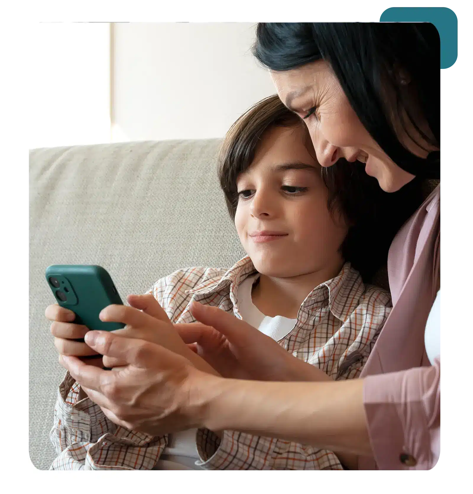Mom and son having fun on the couch with a phone.